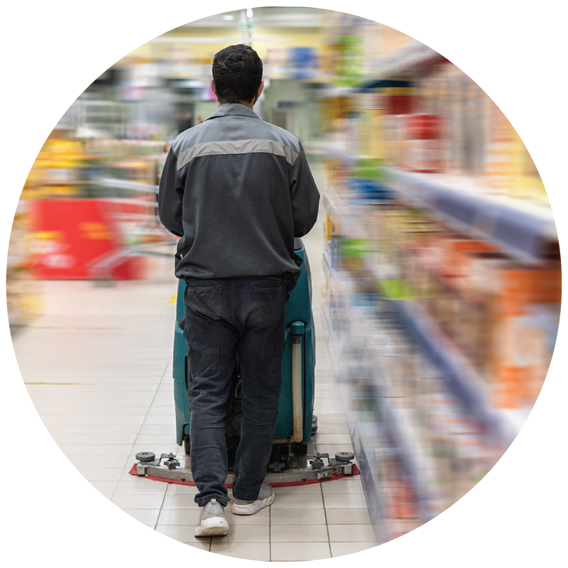 A janitor using floor scrubber to clean supermarket floor