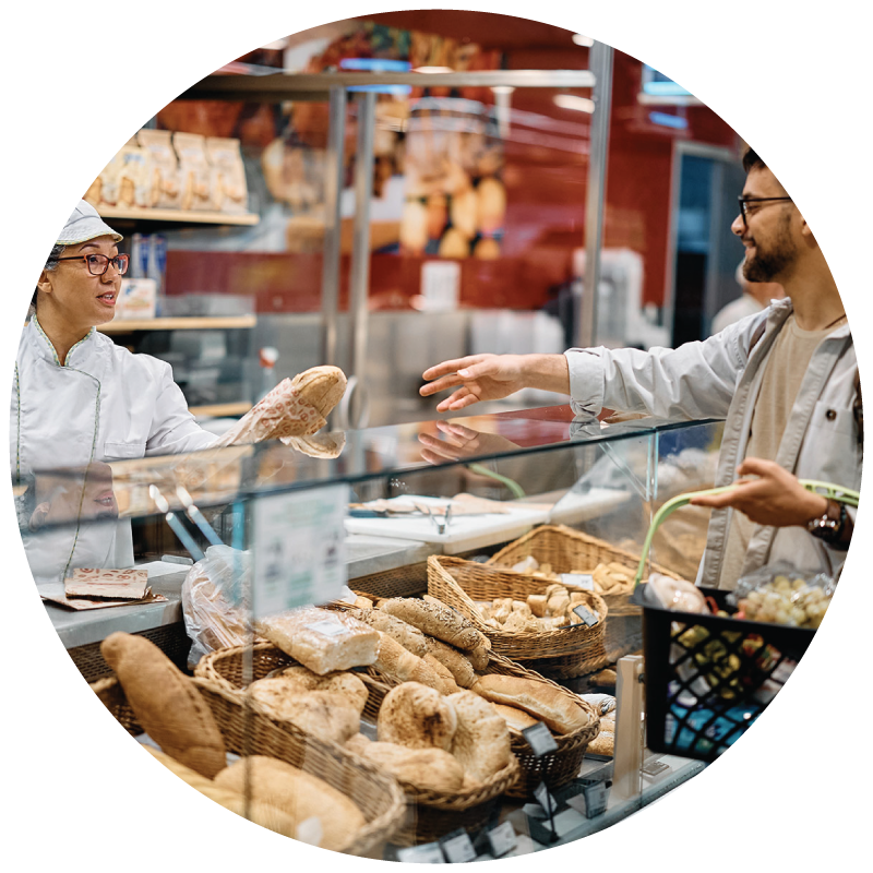 Baker selling bread to a customer at the bakery