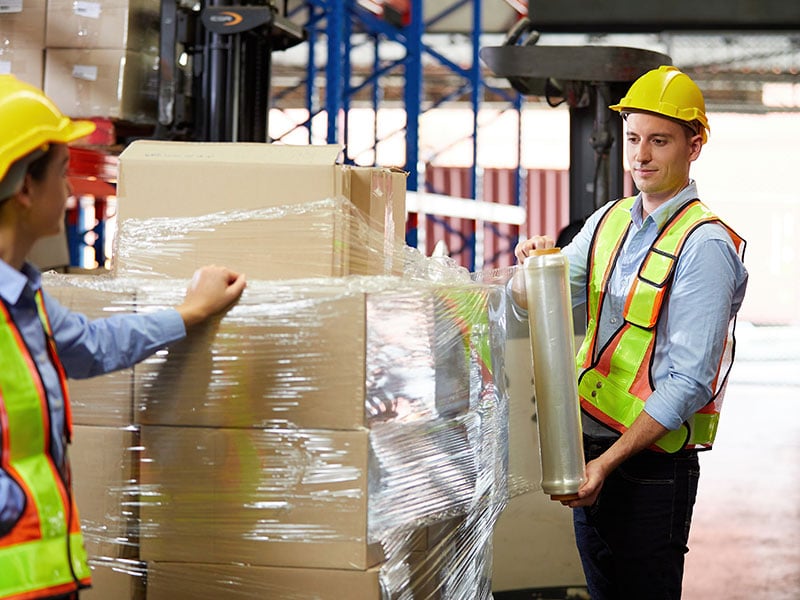 warehouse workers stretch wrapping pallet in a warehouse-packaging solutions