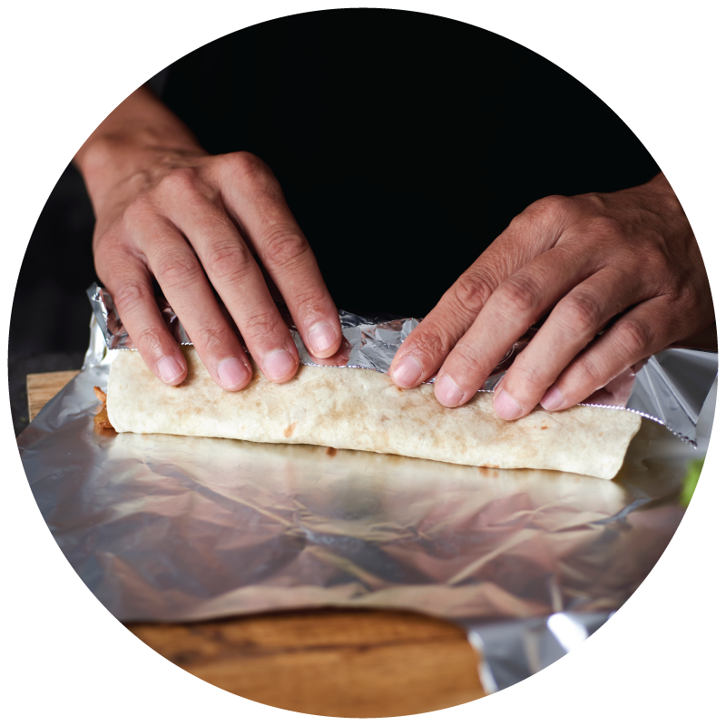 a person wrapping a burrito using aluminum foil in the restaurant