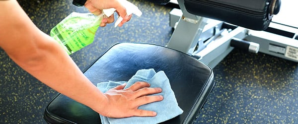 a staff disinfecting and cleaning gym equipment at the hotel gym