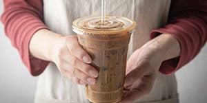 server holding disposable cup with beverage in it