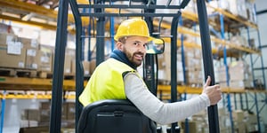 A warehouse worker operating forklift with protective gear on