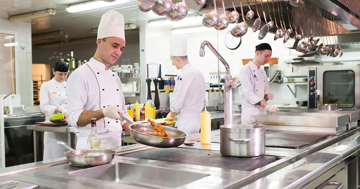 Chefs preparing meals in commercial kitchen for foodservice