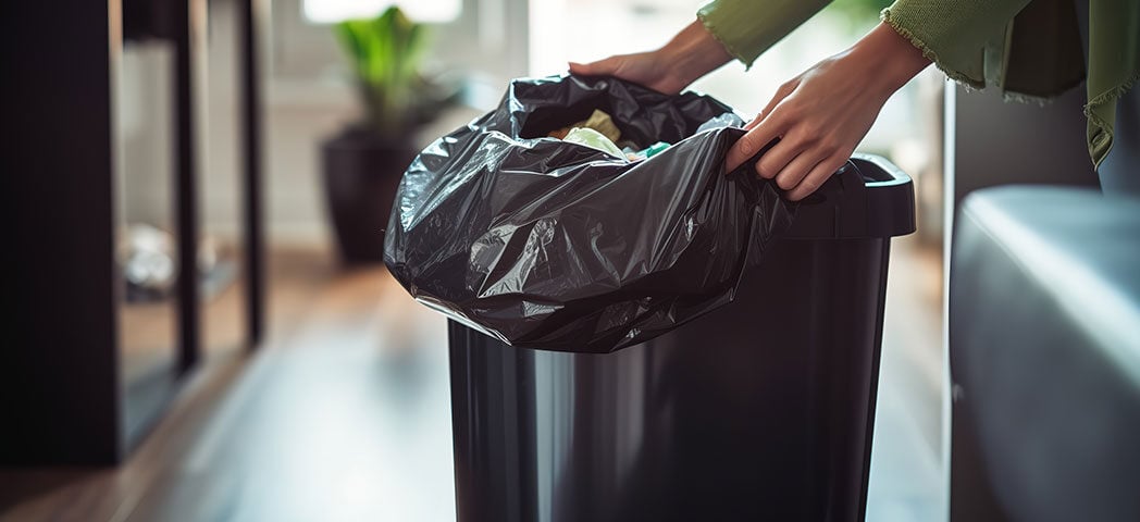 a person pulling out can liner from the trash can
