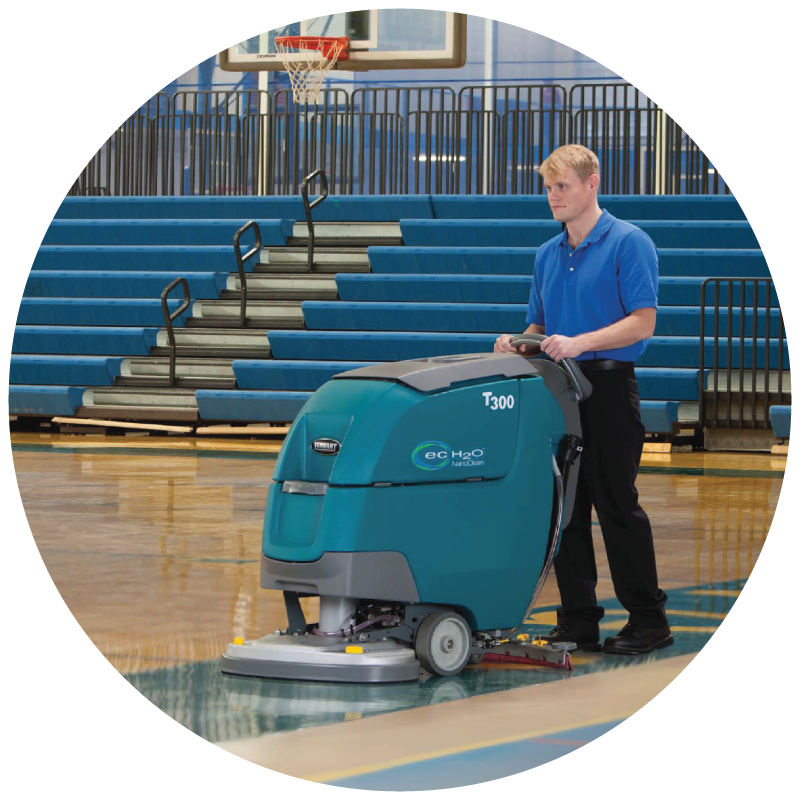 A custodian using floor scrubber to clean gym floor