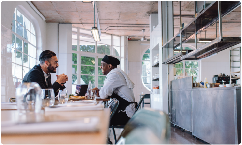 A vendor rep sitting with chef in the commercial kitchen for consultation for foodservice