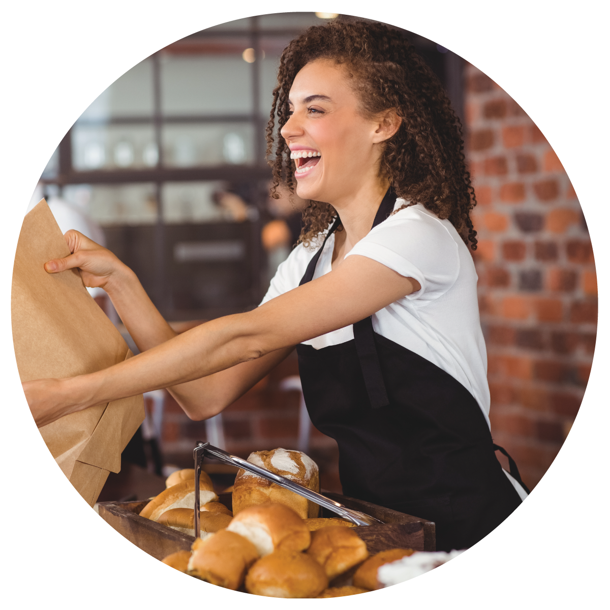 A bakery worker handing out pastry over the counter