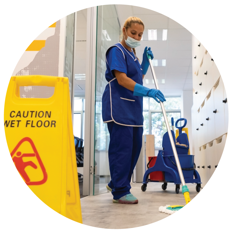 A janitor mopping the floor with wet floor sign in a commercial building