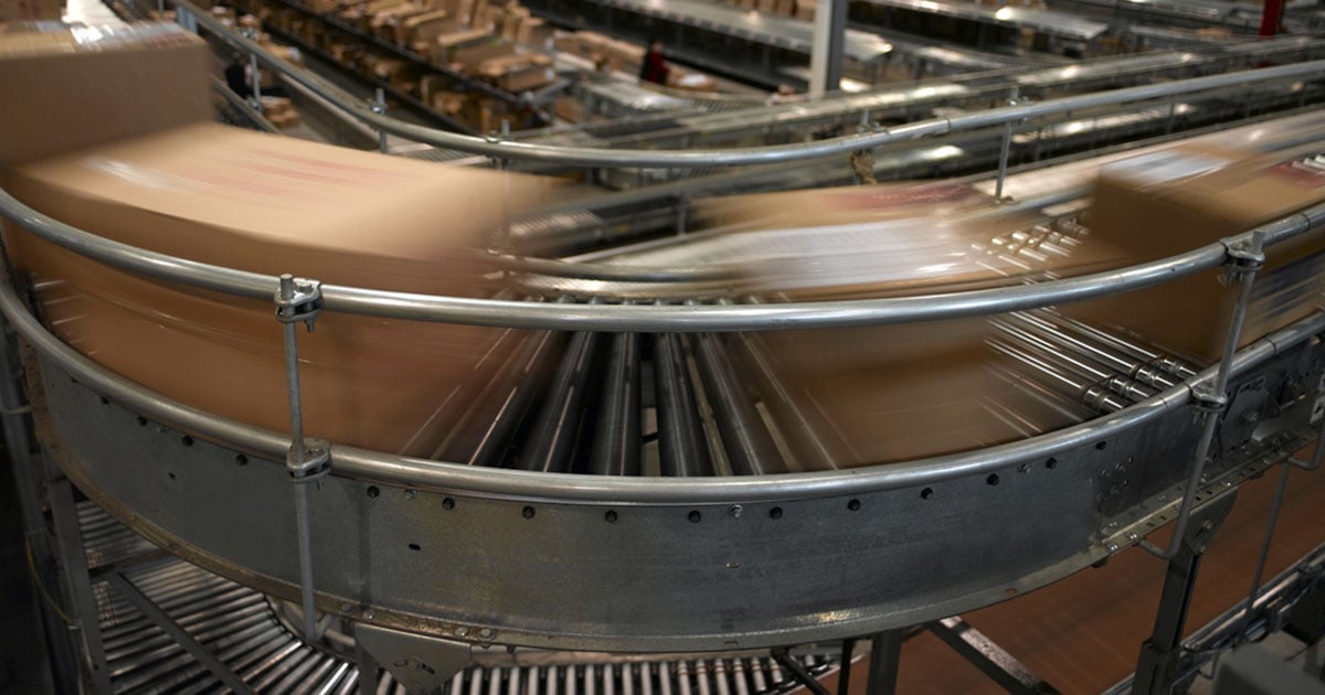 An automated packaging system with conveyor belt showing many boxes moving in a distribution center