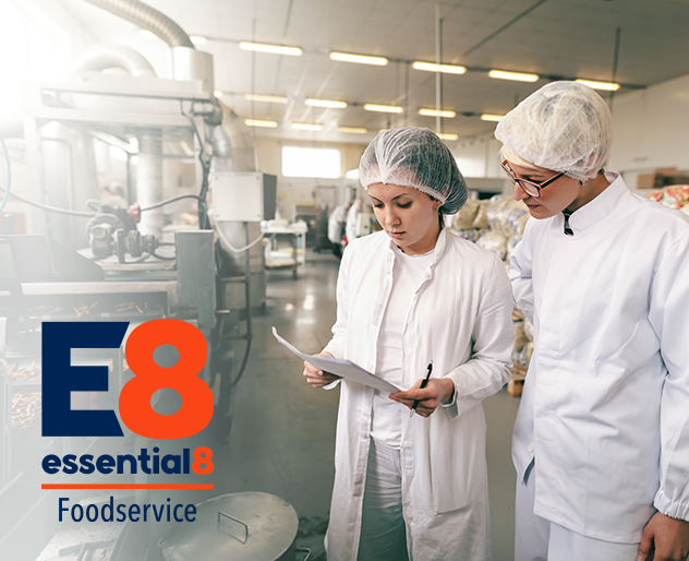 two female staff looking at a document wearing protective clothes and hairnet at the food processing facility