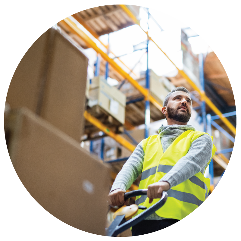 A warehouse worker pulling a flatbed full of shipment in a warehouse