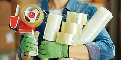 a person holding various shipping supplies, like tape and film - sustainable packaging product solutions