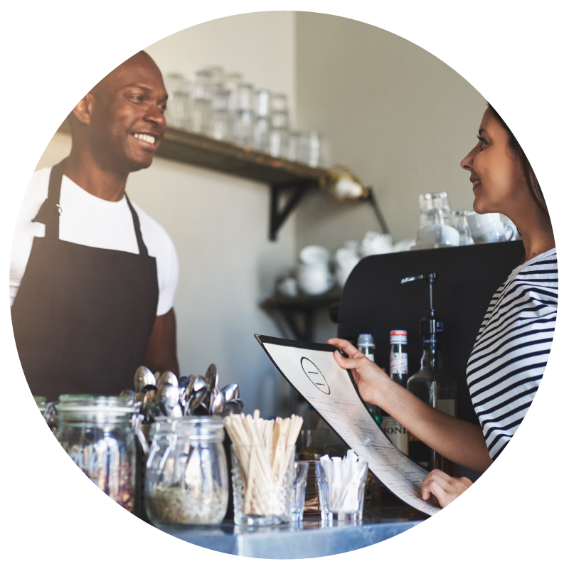 A serving staffing serving a customer over the counter at the commercial kitchen