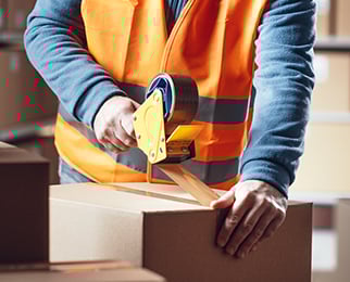 a warehouse staff sealing shipping box with a tape gun