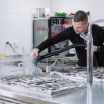 person steam vauuming commercial kitchen grille