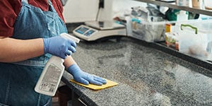 a kitchen staff sanitizing and cleaning kitchen counter surface