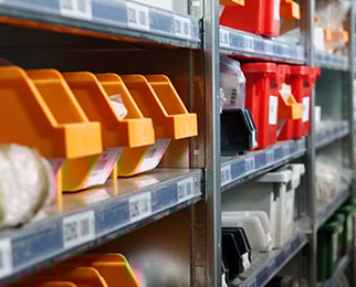 various packaging machine parts organized in bins on shelves