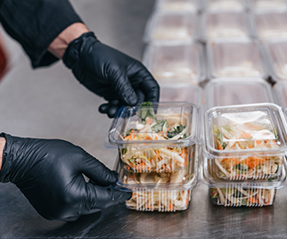 restaurant chef wearing black disposable gloves making to-go orders