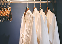 hotel guestroom closet with hangers and shirts hanging