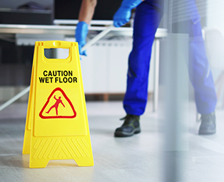 Hard Floor care - a janitor mopping the floor with yellow caution sign