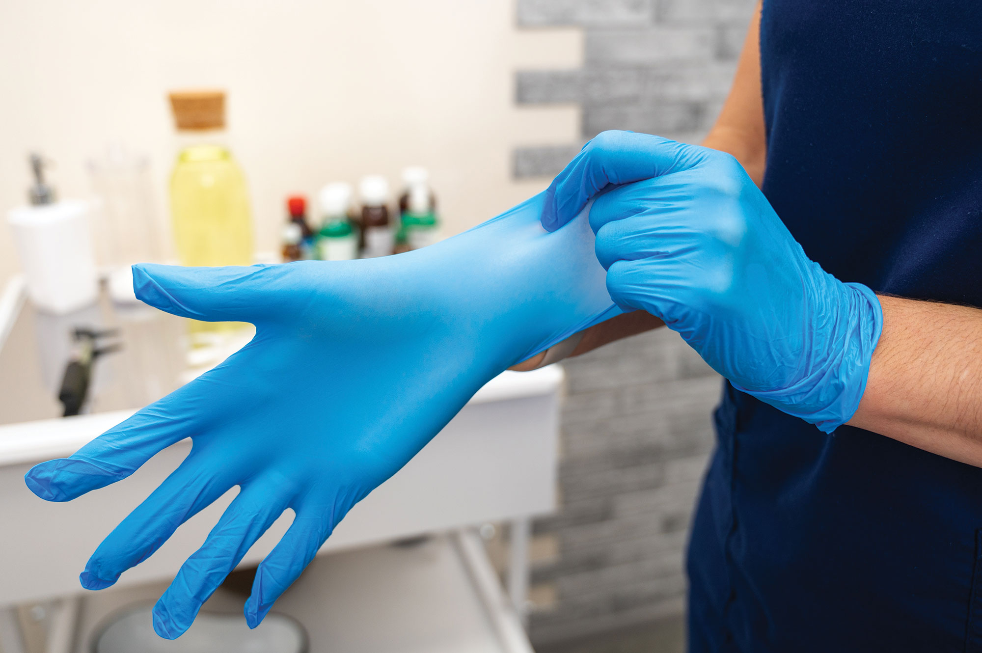 A person wearing blue nitrile goves