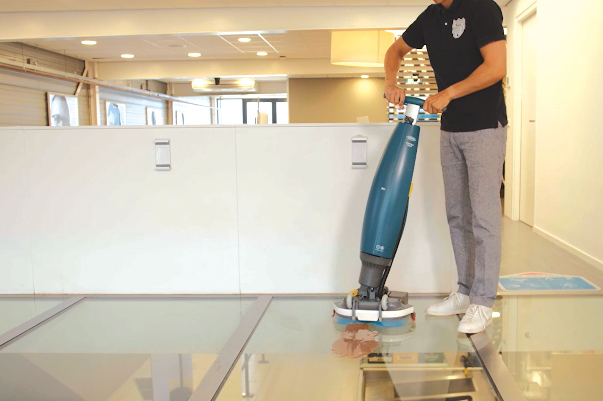 a male custodian using Tennant i-mop Lite to scrub the floor of a facility